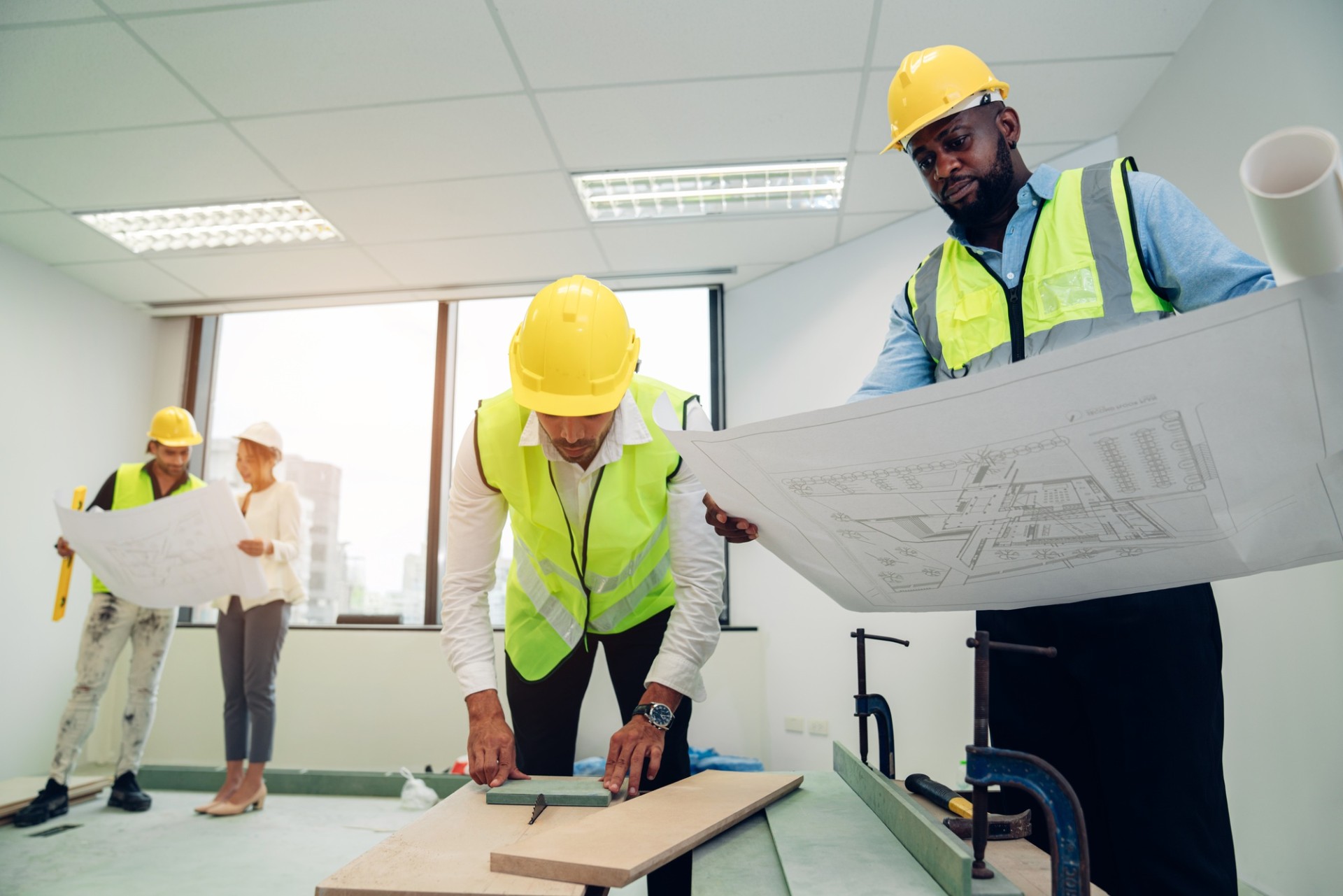 Architector and engineers with draft plan of building on constructing site.